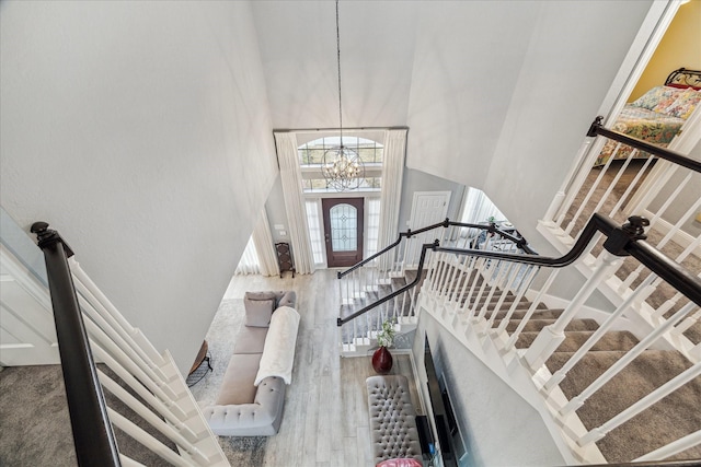 foyer entrance featuring hardwood / wood-style flooring, a towering ceiling, and an inviting chandelier