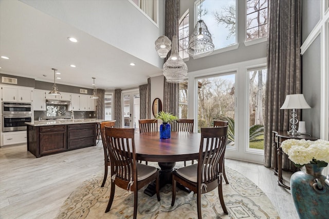 dining room with crown molding and light hardwood / wood-style flooring