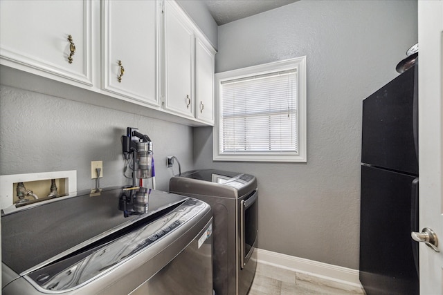 laundry area featuring cabinets, washer and clothes dryer, and light hardwood / wood-style flooring