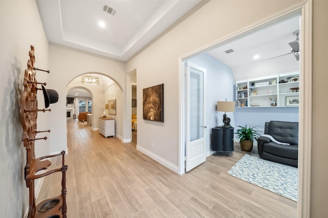 hall with light hardwood / wood-style floors and a tray ceiling