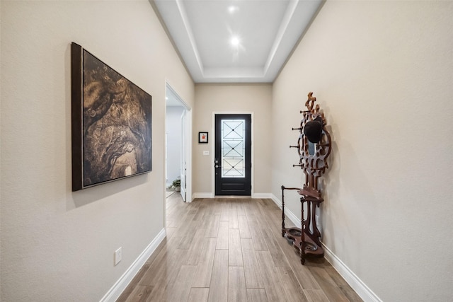 doorway featuring a raised ceiling and light hardwood / wood-style flooring