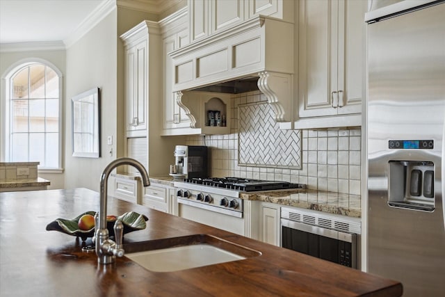 kitchen featuring butcher block counters, sink, backsplash, stainless steel appliances, and crown molding