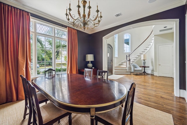 dining area with plenty of natural light, ornamental molding, a chandelier, and light wood-type flooring