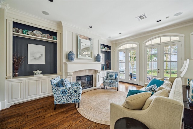 sitting room with crown molding, a premium fireplace, dark hardwood / wood-style floors, built in shelves, and french doors