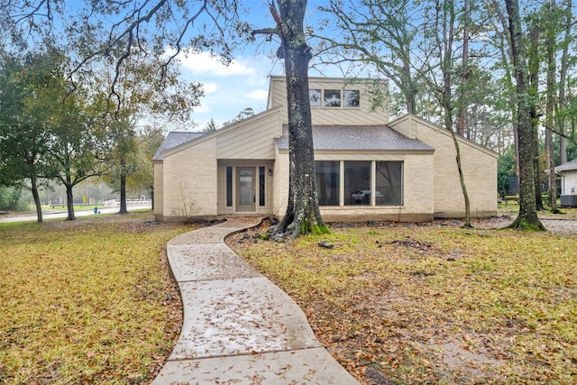 view of front of home with central AC unit and a front lawn