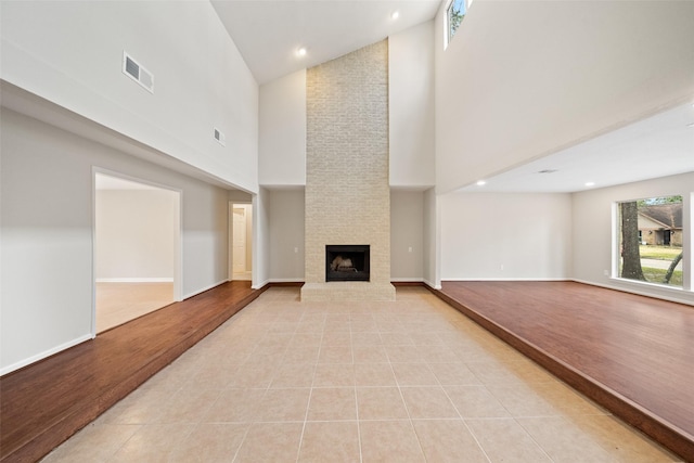 unfurnished living room featuring a fireplace, high vaulted ceiling, and light tile patterned floors