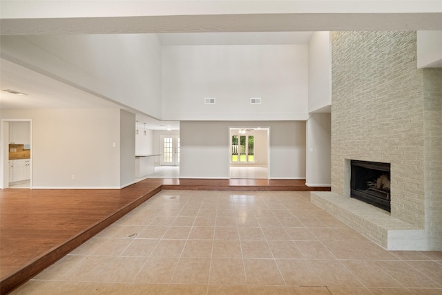 unfurnished living room featuring light tile patterned flooring, a fireplace, and a high ceiling