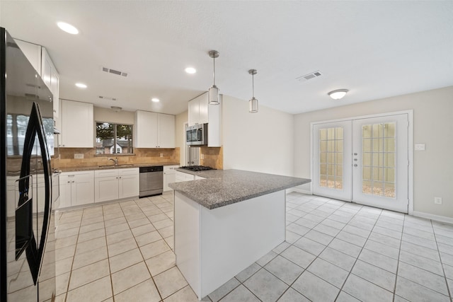 kitchen with appliances with stainless steel finishes, sink, dark stone countertops, white cabinets, and french doors