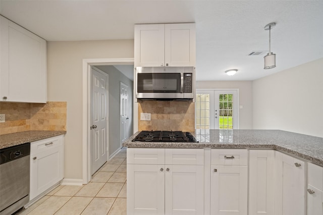 kitchen featuring french doors, light tile patterned floors, appliances with stainless steel finishes, light stone countertops, and white cabinets