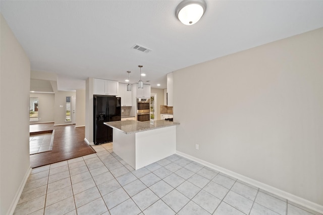 kitchen with light stone counters, white cabinets, light tile patterned flooring, black refrigerator with ice dispenser, and kitchen peninsula