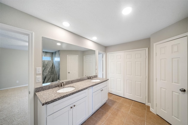 bathroom with tile patterned flooring, vanity, and a textured ceiling