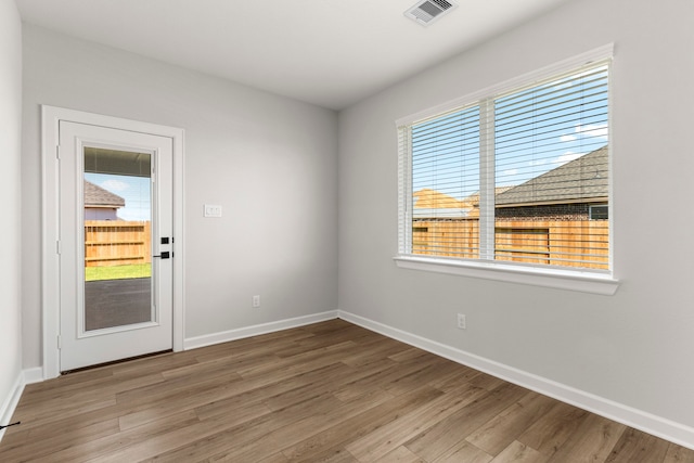 unfurnished room featuring plenty of natural light and wood-type flooring