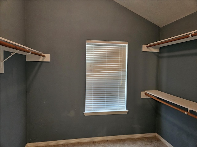 walk in closet with vaulted ceiling and light tile patterned floors