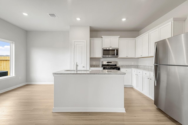 kitchen featuring a center island with sink, white cabinets, and appliances with stainless steel finishes