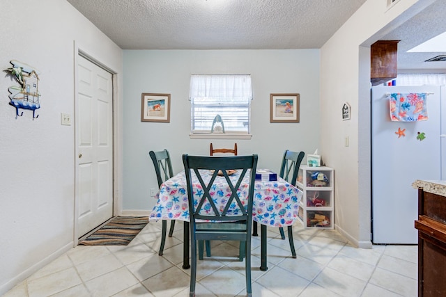 tiled dining room featuring a textured ceiling