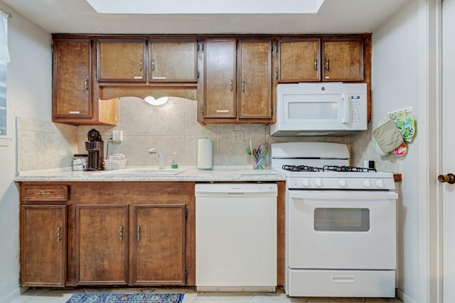 kitchen featuring white appliances, sink, and backsplash