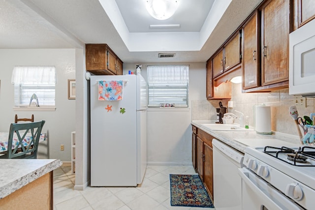 kitchen featuring light tile patterned flooring, sink, tasteful backsplash, a raised ceiling, and white appliances