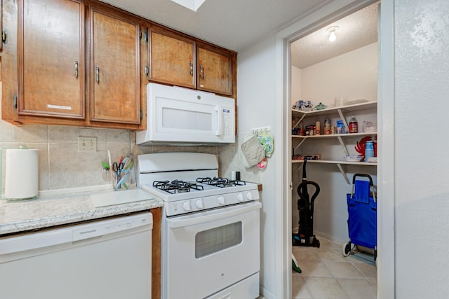 kitchen featuring light tile patterned floors, white appliances, tasteful backsplash, light stone counters, and a textured ceiling