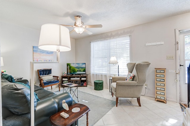 living room with ceiling fan, light tile patterned floors, and a textured ceiling