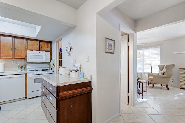 kitchen with light tile patterned floors, white appliances, and backsplash