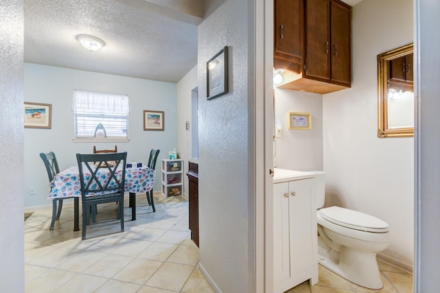 interior space featuring tile patterned flooring, vanity, a textured ceiling, and toilet