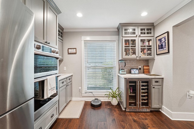 kitchen featuring appliances with stainless steel finishes, tasteful backsplash, gray cabinetry, wine cooler, and dark hardwood / wood-style flooring