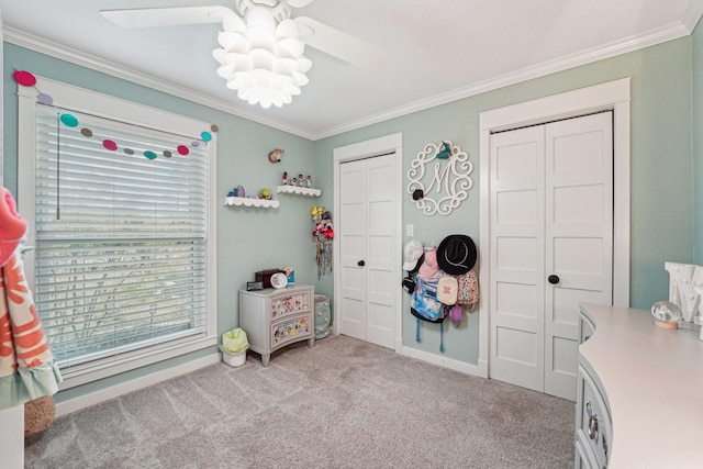 carpeted bedroom with ceiling fan, ornamental molding, and two closets