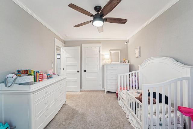 bedroom with crown molding, light colored carpet, ceiling fan, and a crib