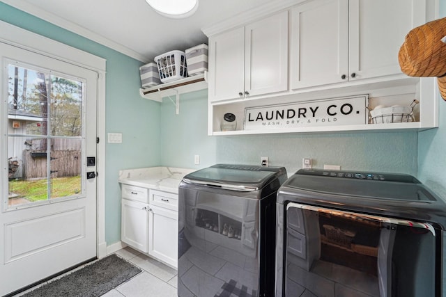 clothes washing area featuring cabinets, ornamental molding, separate washer and dryer, and light tile patterned floors