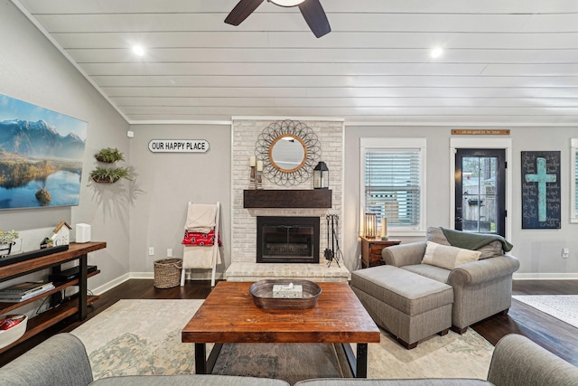 living room featuring ceiling fan, wood-type flooring, ornamental molding, a brick fireplace, and vaulted ceiling