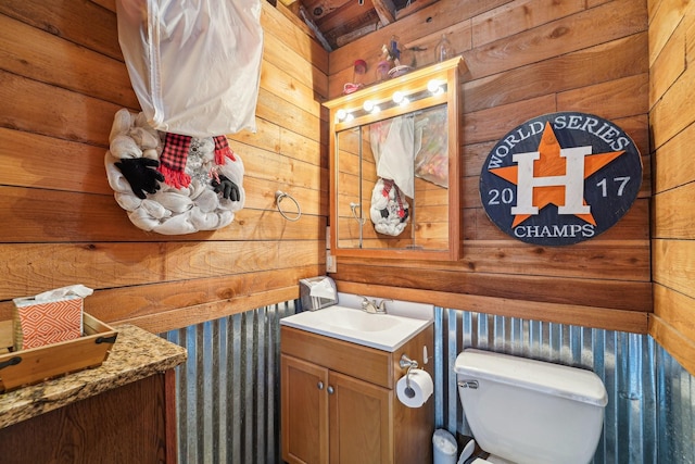 bathroom featuring vanity, toilet, and wood walls