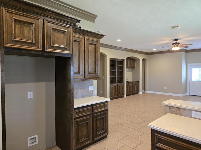 kitchen with backsplash, dark brown cabinetry, ornamental molding, and light tile patterned floors