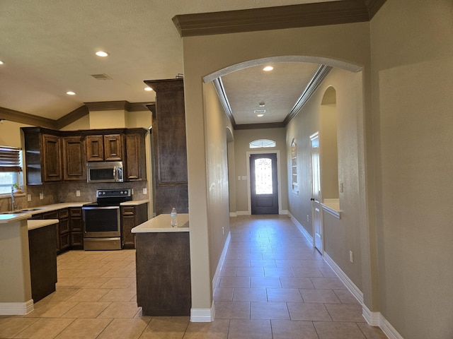 kitchen with dark brown cabinetry, sink, light tile patterned floors, stainless steel appliances, and backsplash