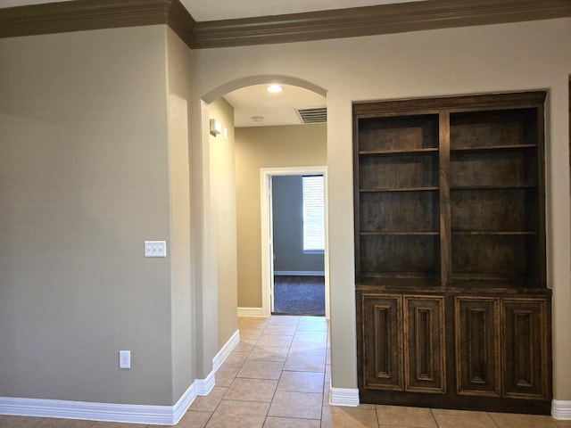 corridor with light tile patterned flooring and ornamental molding