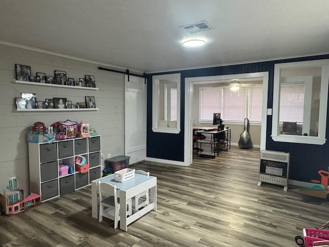 playroom featuring heating unit, hardwood / wood-style floors, and a barn door