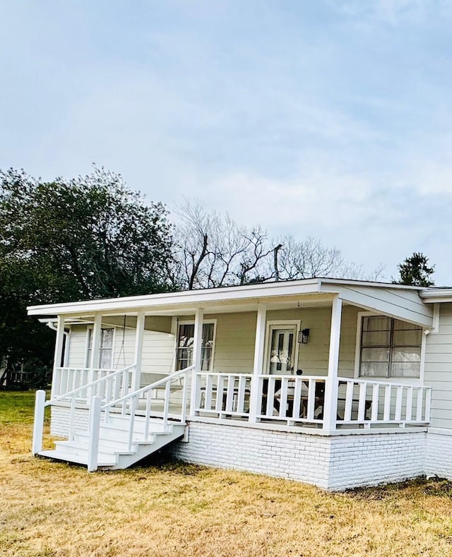 back of house featuring a yard and covered porch