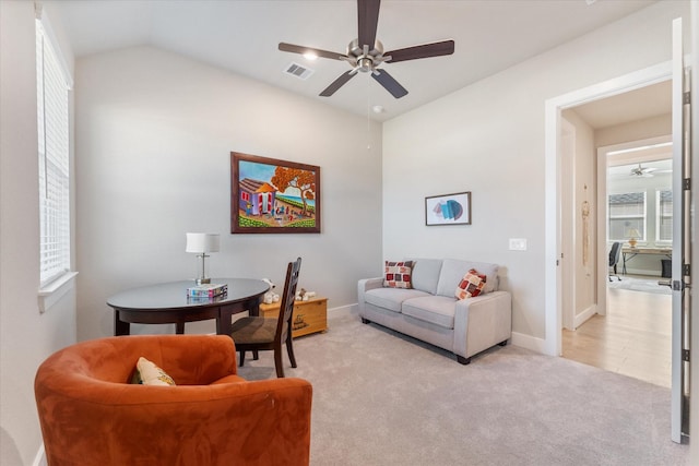 living room with ceiling fan, light colored carpet, and vaulted ceiling