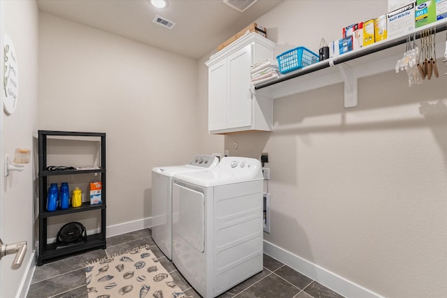 laundry area featuring washer and clothes dryer, cabinets, and dark tile patterned floors