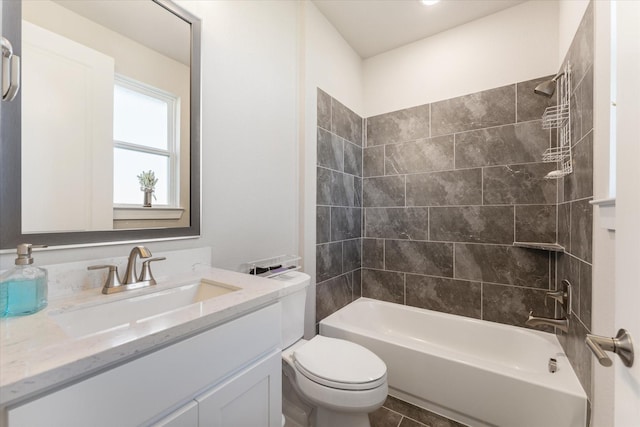 full bathroom featuring tiled shower / bath, vanity, and toilet