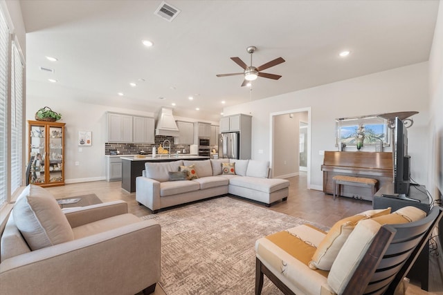 living room with ceiling fan, sink, and light wood-type flooring