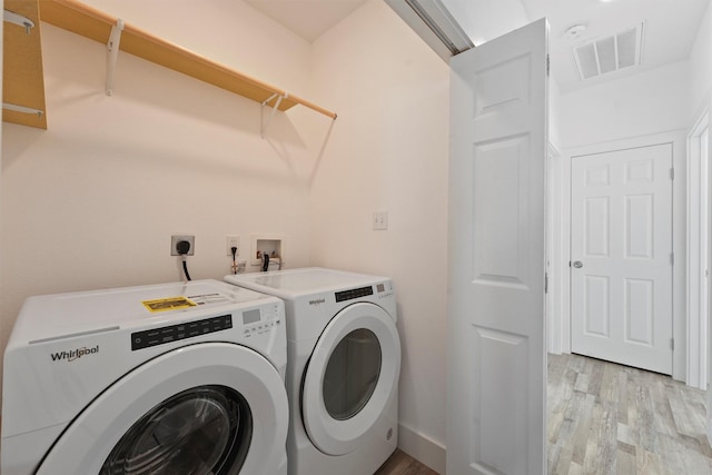 laundry room with separate washer and dryer and light wood-type flooring