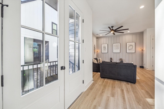 doorway to outside featuring wooden walls, light hardwood / wood-style floors, and ceiling fan