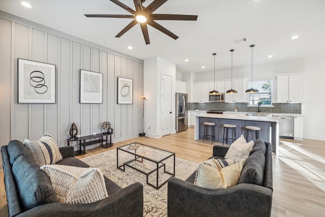 living room with sink, light hardwood / wood-style flooring, and ceiling fan