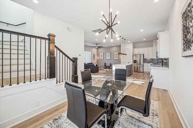 dining room featuring sink, ceiling fan with notable chandelier, and light hardwood / wood-style flooring