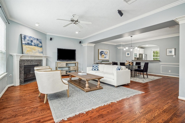 living room with a premium fireplace, ornamental molding, ceiling fan, and dark hardwood / wood-style flooring