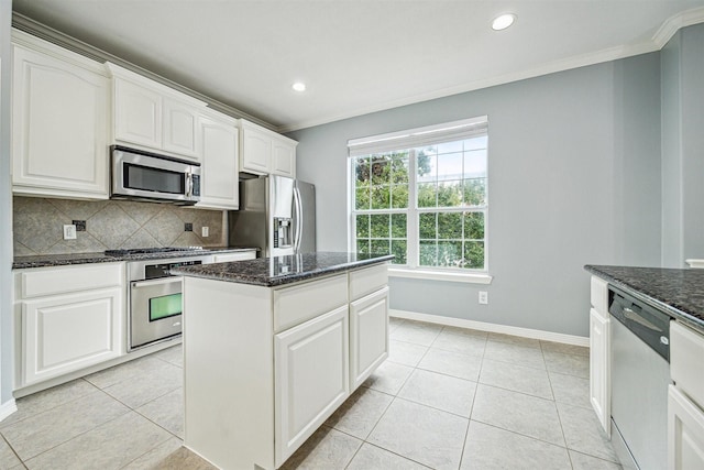 kitchen with stainless steel appliances, a kitchen island, white cabinets, and dark stone counters