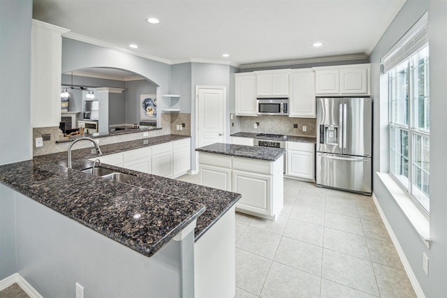 kitchen with appliances with stainless steel finishes, tasteful backsplash, sink, white cabinets, and kitchen peninsula