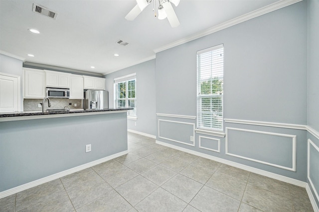 kitchen with light tile patterned floors, crown molding, white cabinetry, stainless steel appliances, and decorative backsplash