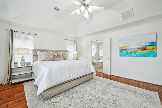 bedroom with a raised ceiling, ceiling fan, dark wood-type flooring, and ensuite bath