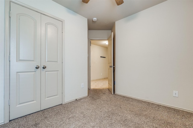 unfurnished bedroom with ceiling fan, light colored carpet, and a closet